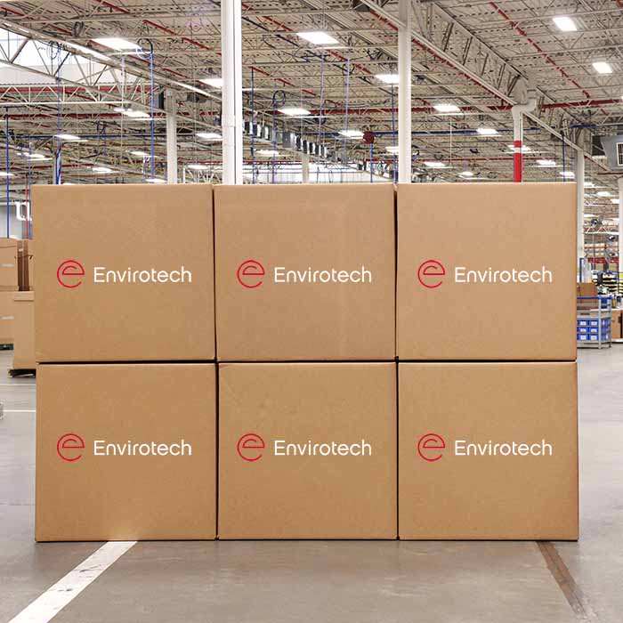 Cardboard boxes stacked in a warehouse with the Envirotech logo on the side of them.