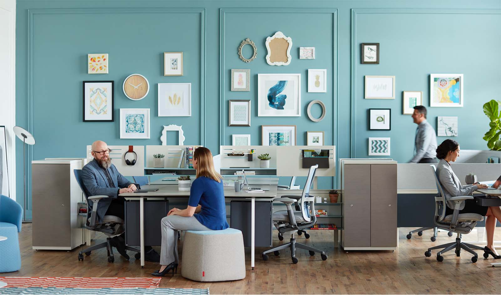 Coworkers sitting at desks and collaborating in an open concept office space.