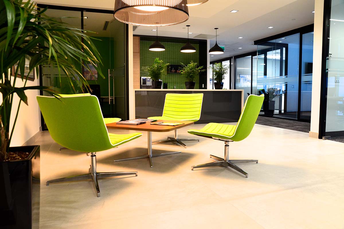 Seating area in an office space with green chairs and a table.