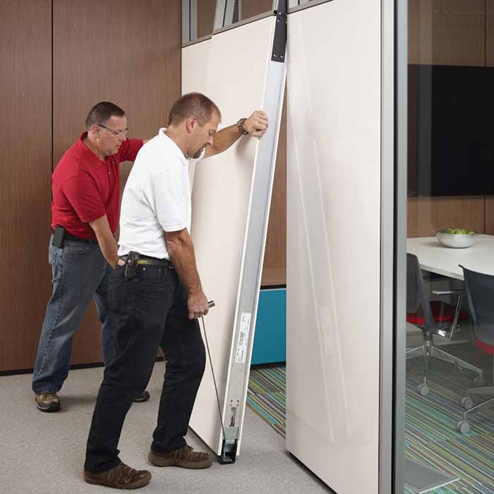 Two men installing a wall in an office space.
