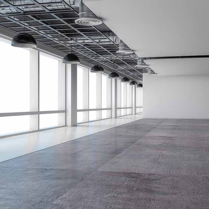 Empty office space with cement floors and large floor-to-ceiling windows.