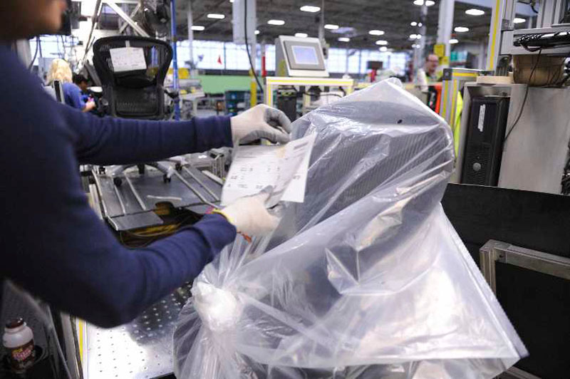 Worker placing a label on recently remanufactured furniture piece.